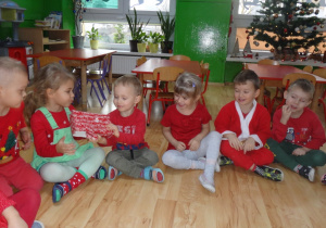 Dzieci siedzą w kole i podają sobie prezent
